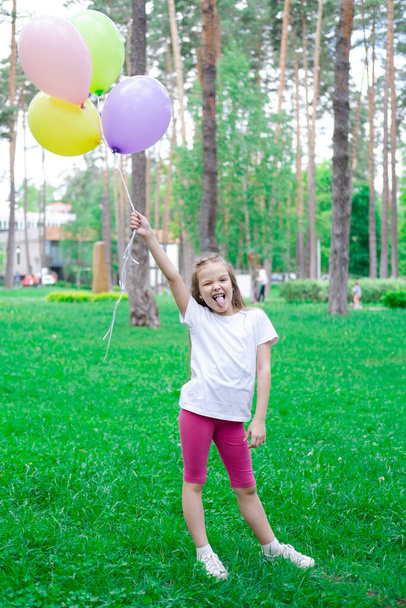 όμορφο κορίτσι προσχολικής ηλικίας που διασκεδάζει παίζοντας με αερόστατα θερμού αέρα σε εξωτερικούς χώρους. Χόλιντεϊ, πάρτι, γενέθλια, γιορτή. ευτυχισμένα παιδιά - Φωτογραφία, εικόνα