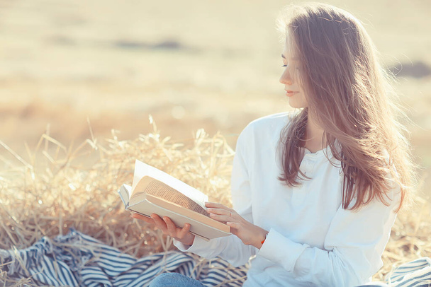 fêmea lendo um livro em um campo de verão mulher palha lendo um livro estudante estudando férias de verão da menina da escola no campo - Foto, Imagem
