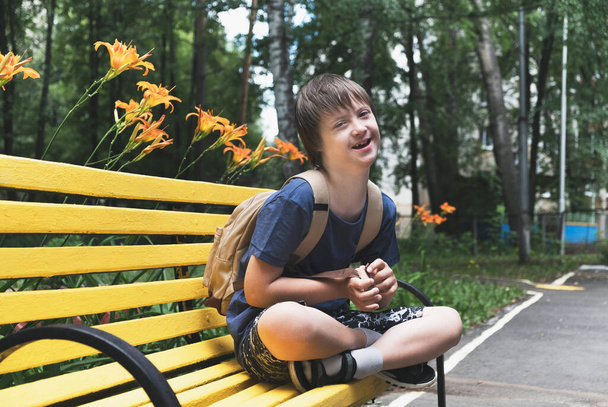 Glücklicher Junge mit Down-Syndrom und Rucksack, bereit für den Schulbesuch. Kind mit Behinderung im Alltag - Foto, Bild