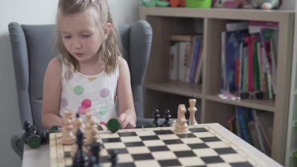 Közelkép, egy kislány mutat darabokat egy sakktáblán otthon. - Felvétel, videó