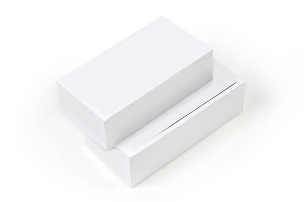 Dos cajas de cartón rectangulares cerradas se encuentran una encima de la otra sobre un fondo blanco - Foto, imagen