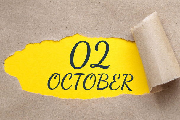october 02. 02th day of the month, calendar date.Hole in paper with edges torn off. Yellow background is visible through ragged hole. Autumn month, day of the year concept. - Fotoğraf, Görsel