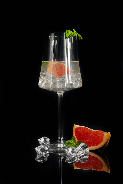 Cocktail with grapefruit on a dark background with a sprig of mint and ice cubes. Isolate. Copy space. - Foto, afbeelding