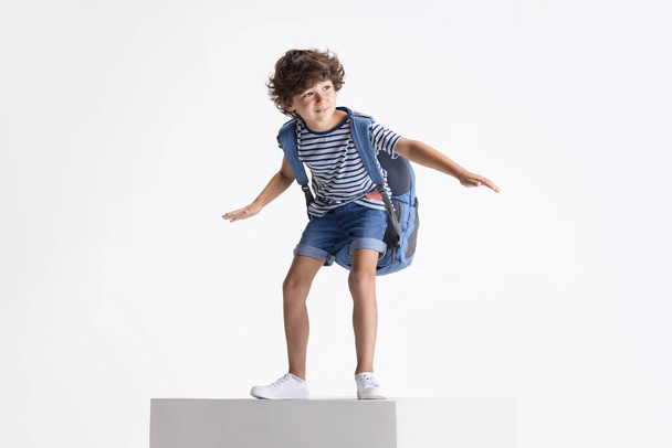 Caucasian preschool boy standing on big box isolated over white studio background. Copyspace. Childhood, education, emotions concept - Foto, Imagen