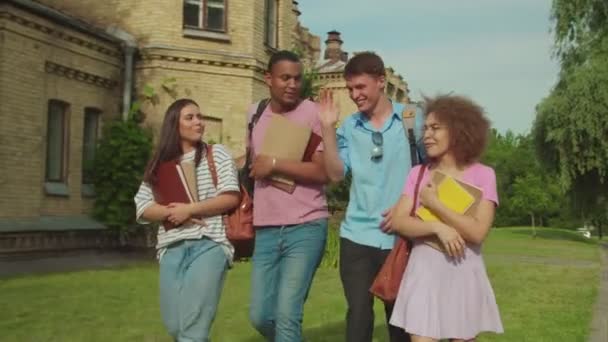 Diverse group of students walking along university building outdoors - Séquence, vidéo