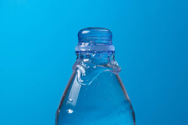 Water is poured out and a plastic bottle on a blue background. Clean drinking water. - 写真・画像