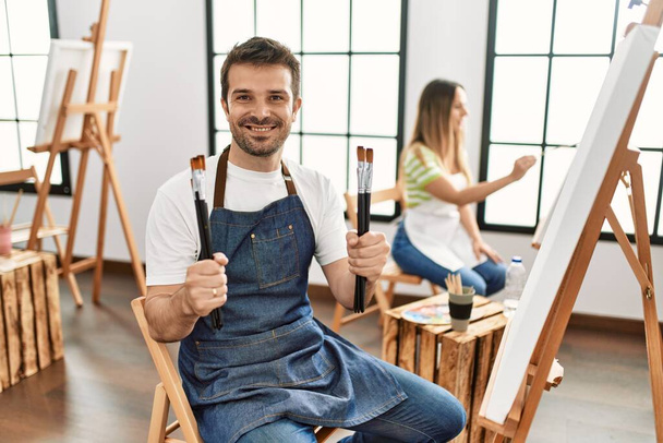 Dos estudiantes hispanos sonriendo feliz pintura en el estudio de arte - Foto, imagen