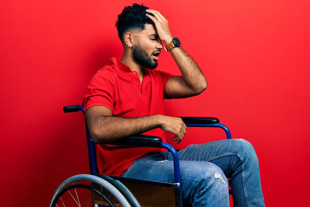 Araber mit Bart, der im Rollstuhl sitzt, überrascht mit der Hand auf dem Kopf für Fehler, erinnere dich an Fehler. Vergessenes, schlechtes Gedächtnis.  - Foto, Bild