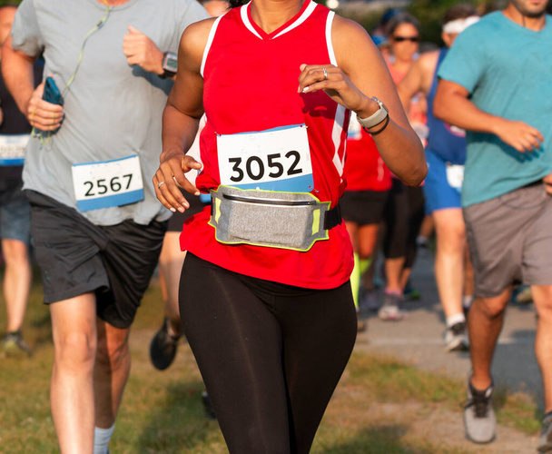 Detailní záběr běžci závodní 5K na stezce se ženami na sobě ledvinka kolem pasu nést její osobní iteams. - Fotografie, Obrázek