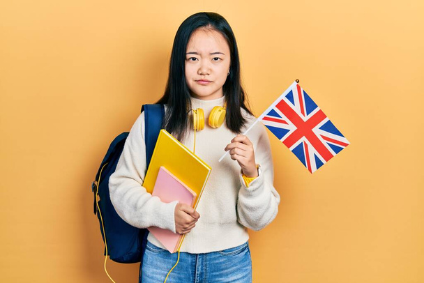 Nuori kiinalainen tyttö vaihto opiskelija tilalla uk lippu skeptinen ja hermostunut, murjottaa järkyttynyt ongelman vuoksi. negatiivinen henkilö.  - Valokuva, kuva