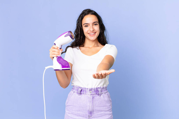 hispanic pretty woman smiling happily with friendly and  offering and showing a concept and holding an iron steam - Photo, Image