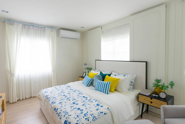 Κίτρινα και μπλε μαξιλάρια σε λευκό κρεβάτι - Φωτογραφία, εικόνα
