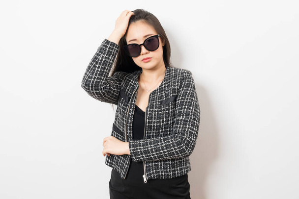 Inteligente e confiante mulher asiática com óculos de sol em terno cinza no fundo branco. - Foto, Imagem