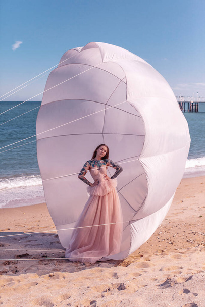 Schöne Frau mit weißem Fallschirm am Strand - Foto, Bild