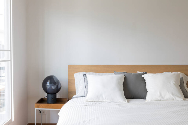 ホテルの寝室のインテリアのライトランプとベッドの装飾に白い枕のクローズアップ. - 写真・画像