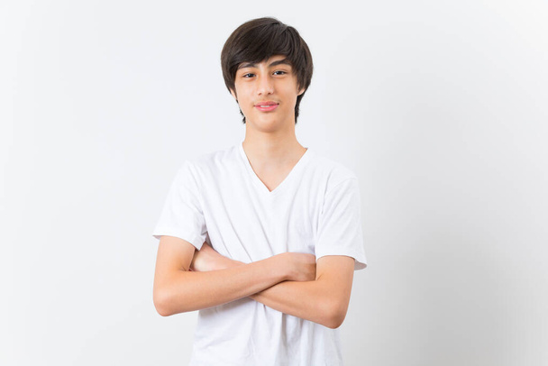 Atractivo chico caucásico adolescente con los brazos cruzados sobre fondo blanco. - Foto, imagen