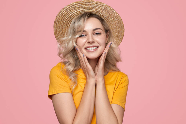 Happy woman in straw hat touching cheeks - Photo, Image
