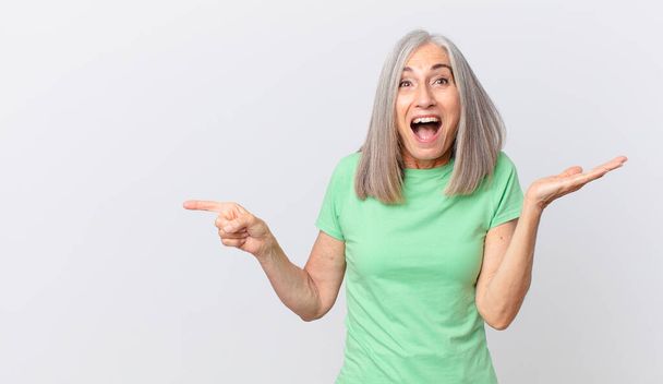 middle age white hair woman feeling happy and astonished at something unbelievable and pointing to the side - Foto, Imagem