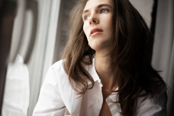 Close-up portrait of a beautiful young sensual woman with long dark hair in a white shirt - Photo, image