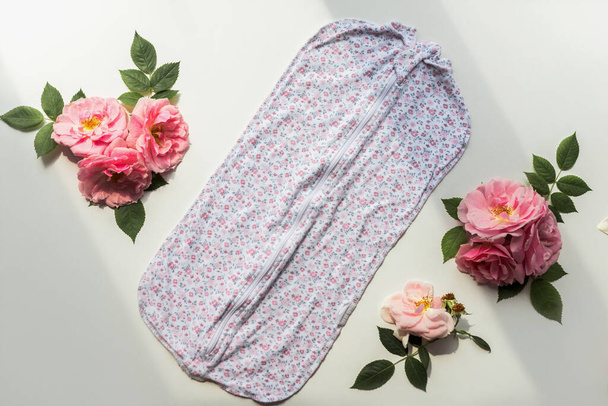 Neugeborener Strampler mit Blumenmuster und Rosen-Komposition. Isoliert auf weißem Hintergrund - Foto, Bild