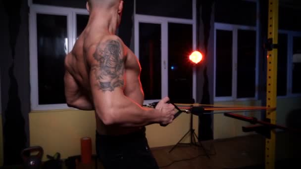 Hezký svalnatý muž dělá cvičení v tělocvičně pomocí rezistentních pásem - Záběry, video