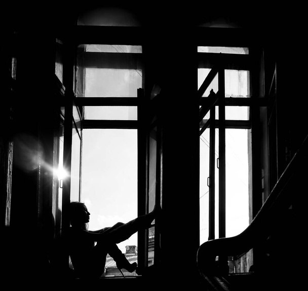 silhouette of dreaming woman sitting on  the window sill.  old entrance in Saint Petersburg - Fotó, kép