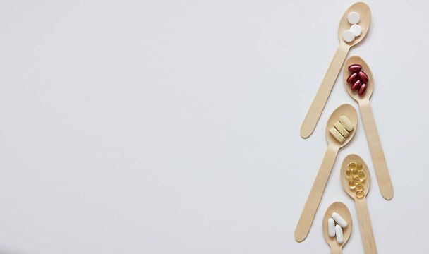 Integratori alimentari e vitamine su cucchiai di legno su sfondo bianco. Il concetto di prendersi cura della vostra salute e stile di vita sano. Bandiera - Foto, immagini