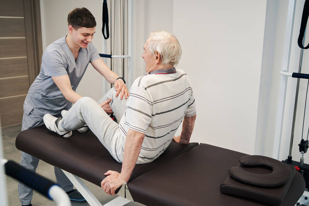 Pozitivní medik pomáhá stárnoucím mužům v ležení na léčebném stole - Fotografie, Obrázek