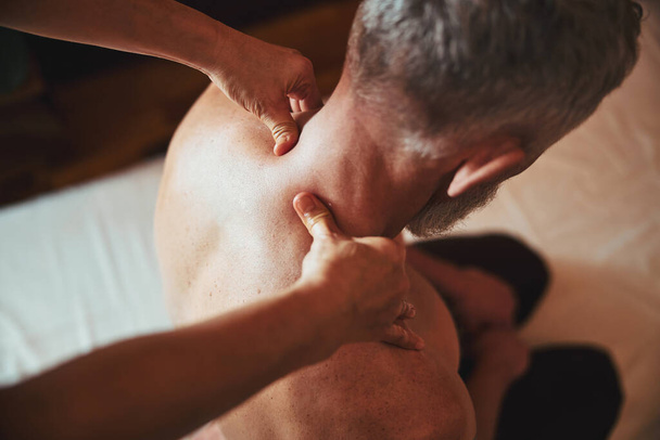 Grizzled man doing massage for healing neck - Φωτογραφία, εικόνα