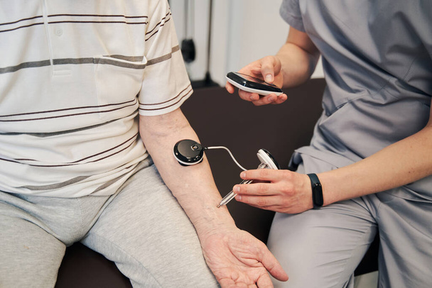 Врач прижимает ручное мышечное тестирование к руке пациента - Фото, изображение