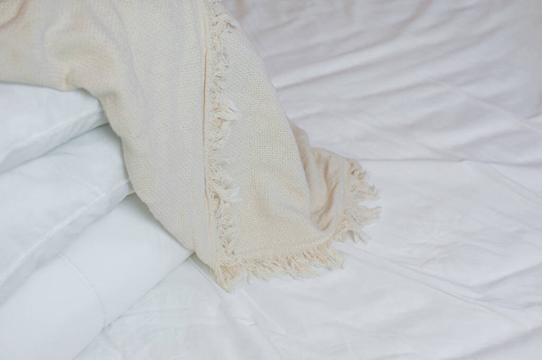 stack of white pillows and blankets lies on the bed on a white sheet on top, covered with a blanket - 写真・画像