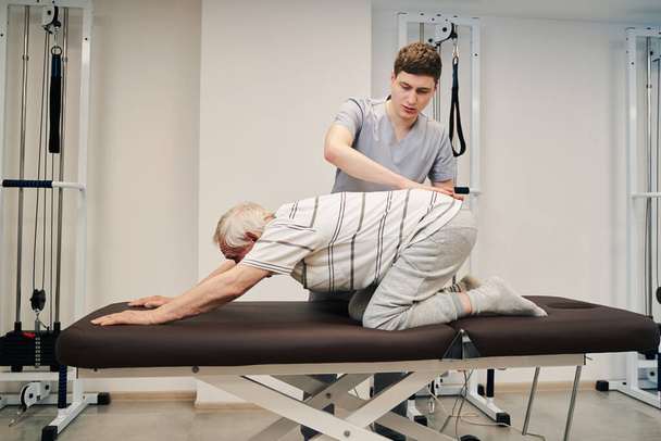 Paciente de edad avanzada en posición propensa que recibe tratamiento del terapeuta - Foto, imagen
