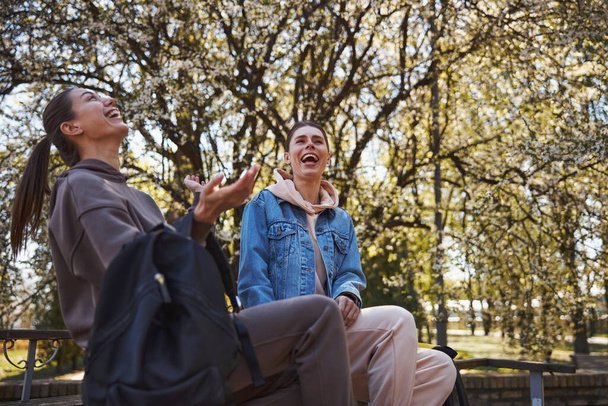 Two women laughing on joke in park - Fotó, kép