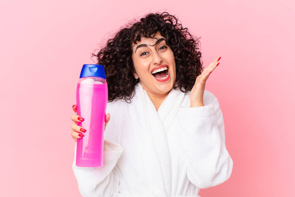 pretty arab woman wearing bathrobe and holding a shampoo bottle - Fotoğraf, Görsel