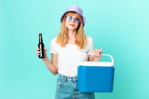 pretty red head woman with a portable refrigerator and a beer - Photo, Image