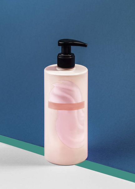 Barattolo di plastica rosa per shampoo, crema isolata su sfondo blu. Una presa in giro. Primo piano - Foto, immagini
