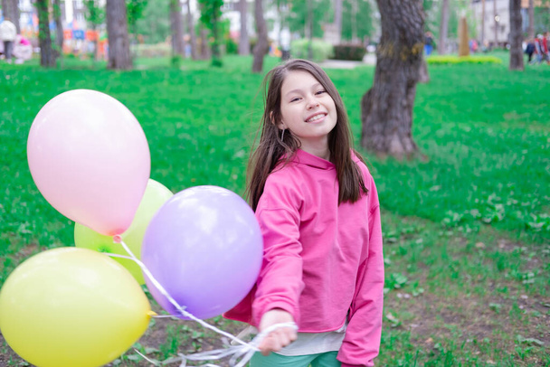 mooi tussen tiener brunette meisje in roze houden kleurrijke hete lucht ballonnen buiten. Feest, verjaardagsconcept. Zomertijd. gelukkige kinderen. vakantie, zomervakantie. - Foto, afbeelding