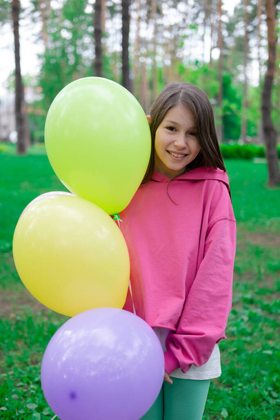pretty tween teenager brunette girl in pink holding colorful hot air balloons outdoors. party, birthday concept. summertime. happy children. hollidays, summer break. - Photo, Image