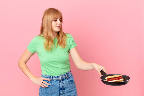 pretty red head woman cooking a hotdog with a pan - Photo, Image