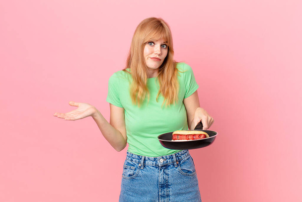 pretty red head woman cooking a hotdog with a pan - 写真・画像