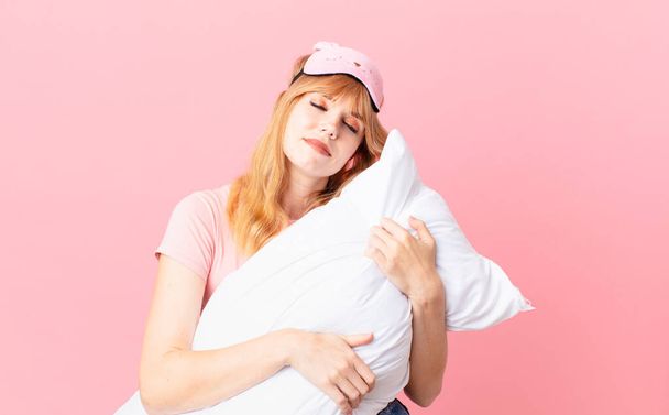 pretty red head woman wearing pajamas and holding a pillow - 写真・画像