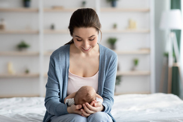 A fiatal boldog nő otthon tölti az idejét az újszülött kisbabájával - Fotó, kép