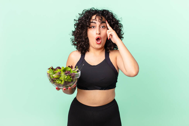 pretty arab woman looking surprised, realizing a new thought, idea or concept and holding a salad. diet concept - Zdjęcie, obraz
