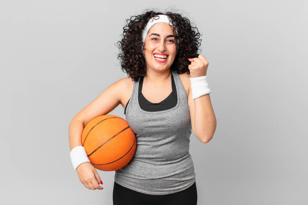 jolie femme arabe se sentant choquée, riant et célébrant le succès et tenant un ballon de basket-ball. concept sportif - Photo, image