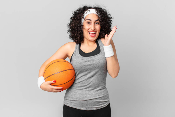 pretty arab woman feeling happy and astonished at something unbelievable and holding a basketball ball. sport concept - Foto, afbeelding
