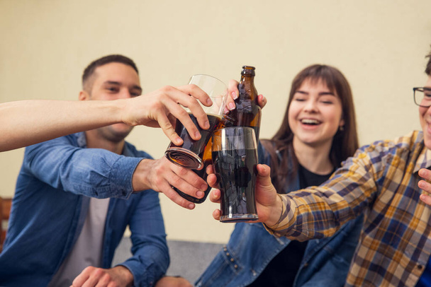 Cheers. Four young people, sportive fans meeting together in bar, pub. Concept of friendship, leisure activity, emotions and sport event - Foto, Bild