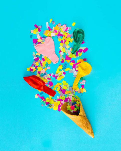 An ice cream cone from which confetti comes out. Celebration, party. Blue background. - Photo, Image