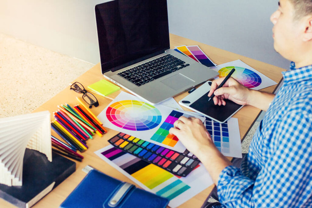Designer Grafik kreativ, hält Mausstift, arbeitet Laptop im Büro mit Sonnenuntergang Hintergrund, Selektiver Fokus. - Foto, Bild