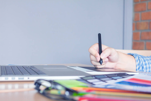 Дизайнер графический креативный, с ручкой мыши, рабочий ноутбук в офисе с закатом фона, выборочный фокус. - Фото, изображение