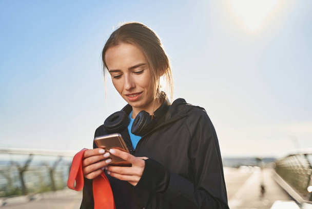 Kikapcsolt nő üzenetküldés okostelefonon edzés után a szabadban - Fotó, kép